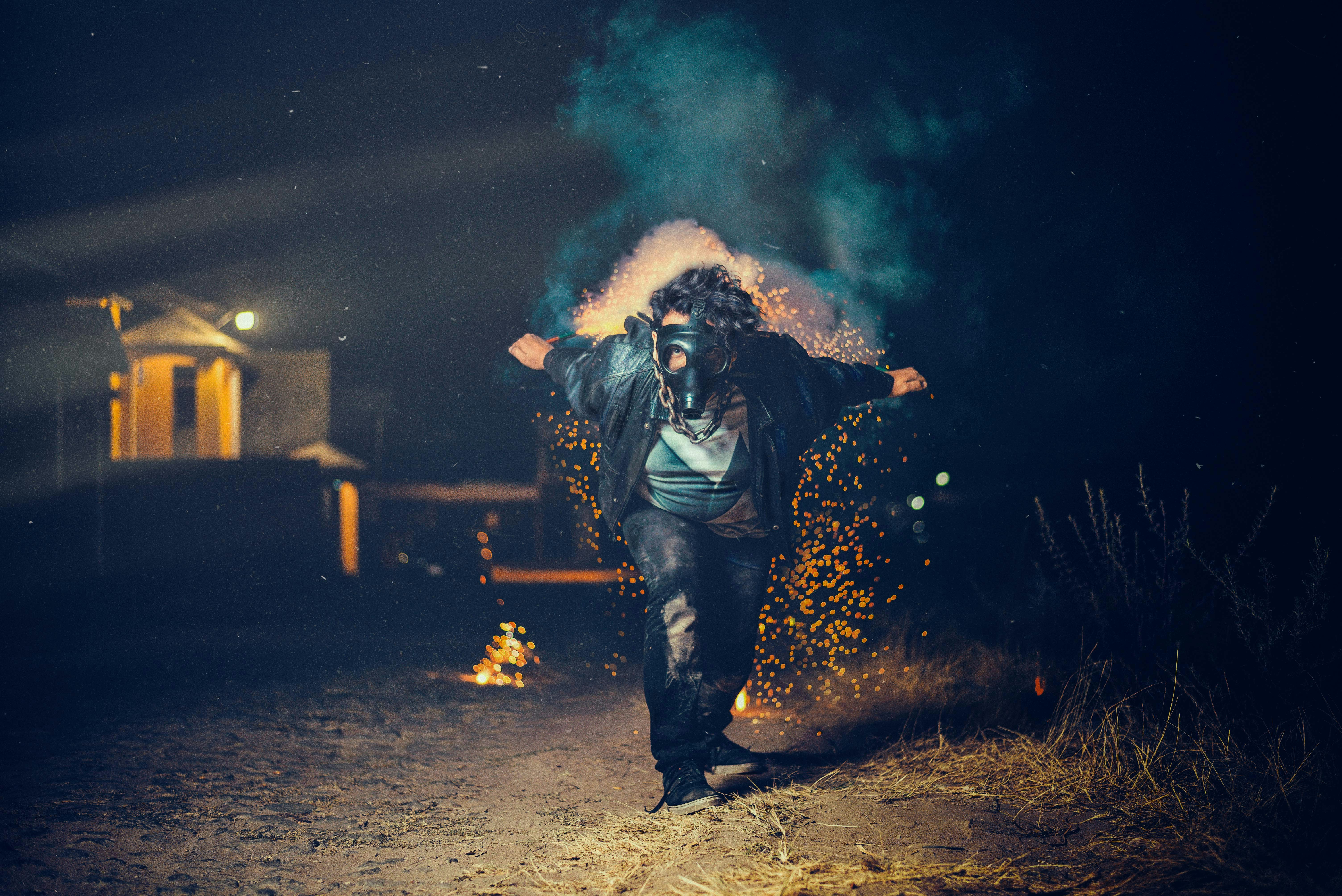 low-light photo of man wearing gas mask bong about to run in between of green grass